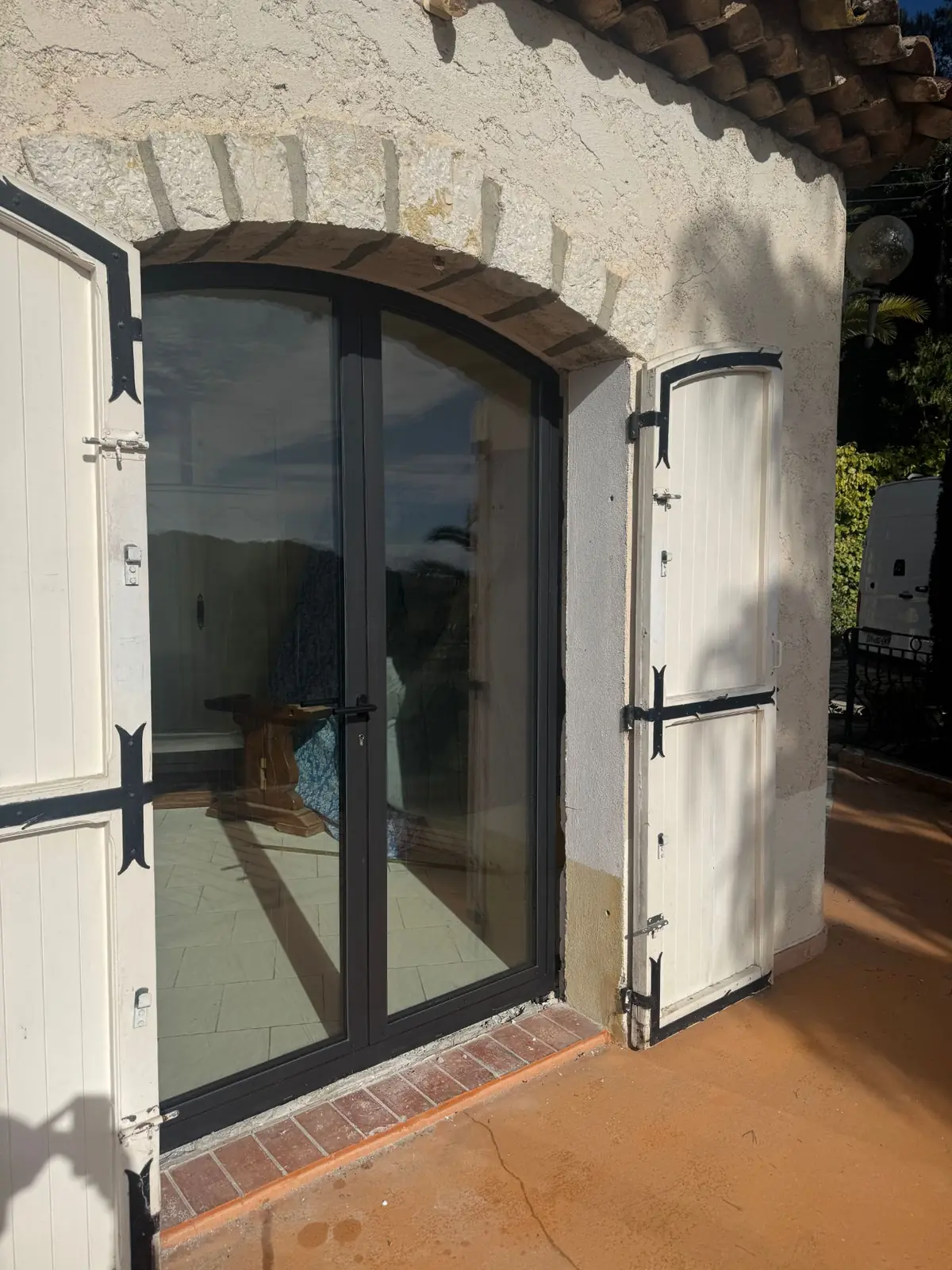 Porte-fenêtre cintrée en profilés acier JANSEN à rupture de pont thermique sous un arc en pierre, villa à Antibes