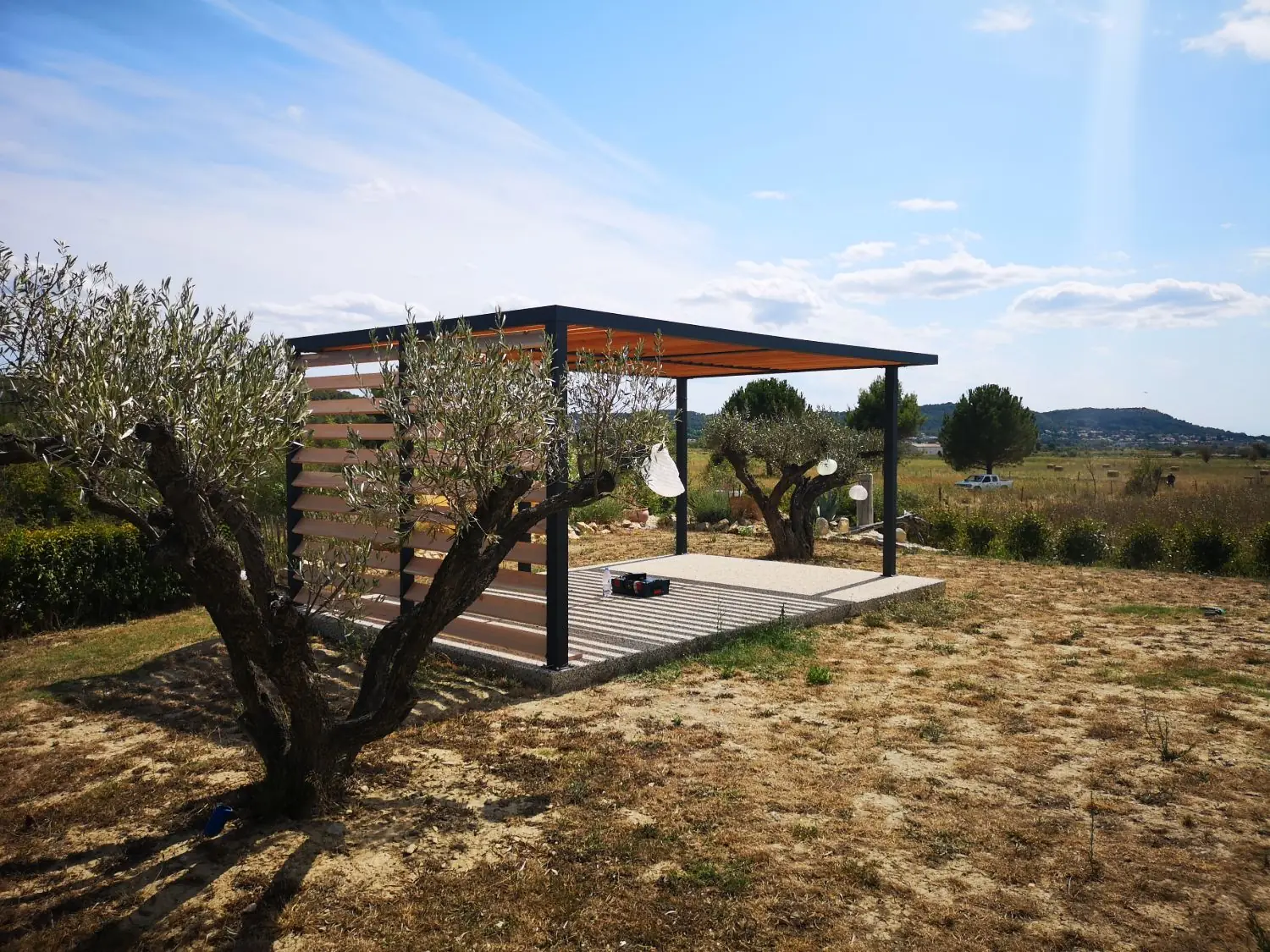Pergola autoportante sur mesure avec claustra en lames de bois Douglas sur le petit côté, au milieu des oliviers, Caveirac (Gard)