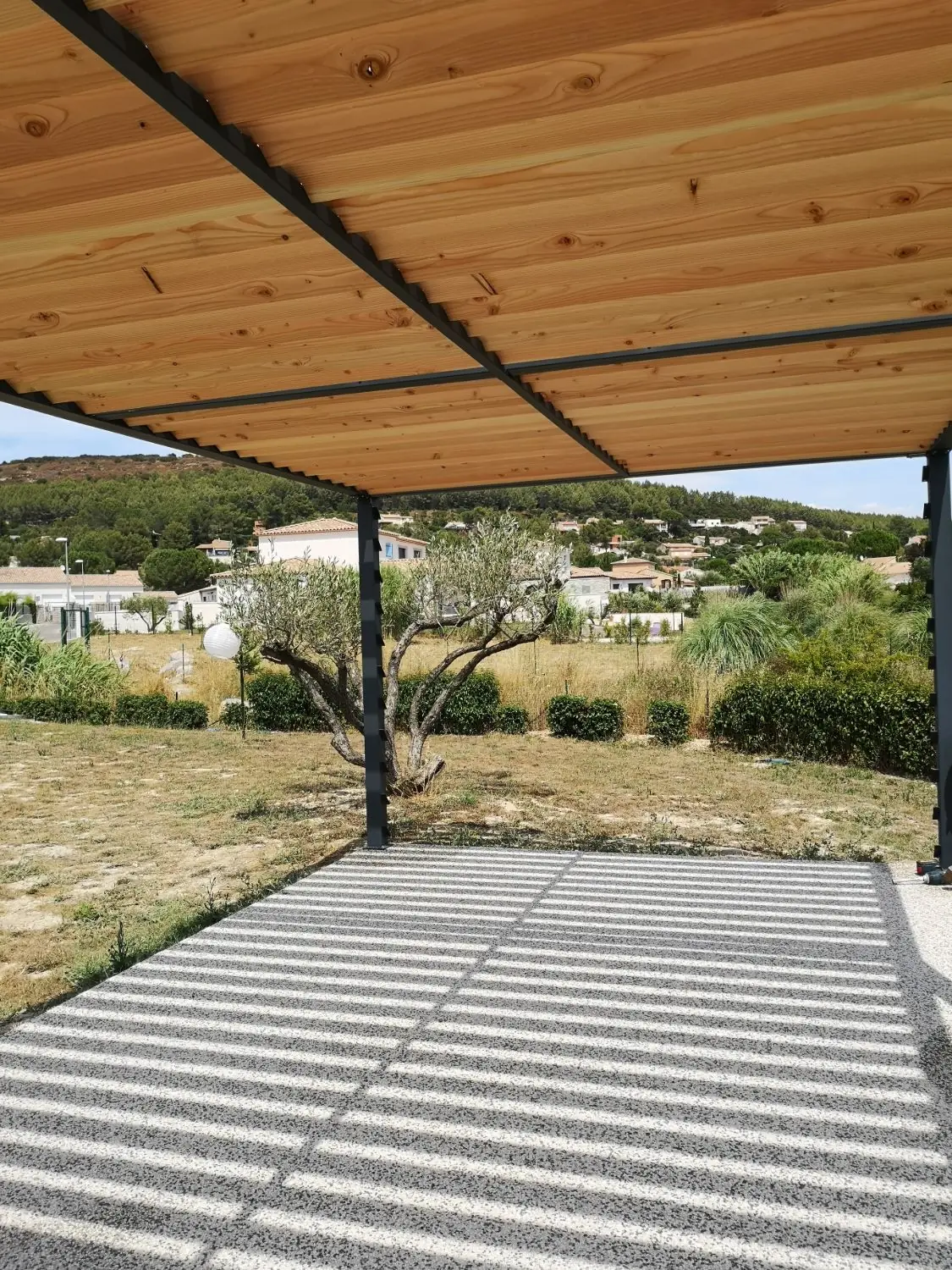 Sous-face de la pergola autoportante : lames de bois Douglas traité posées sur les poutres thermolaquées RAL 7016, ombres rayées sur la dalle, Caveirac