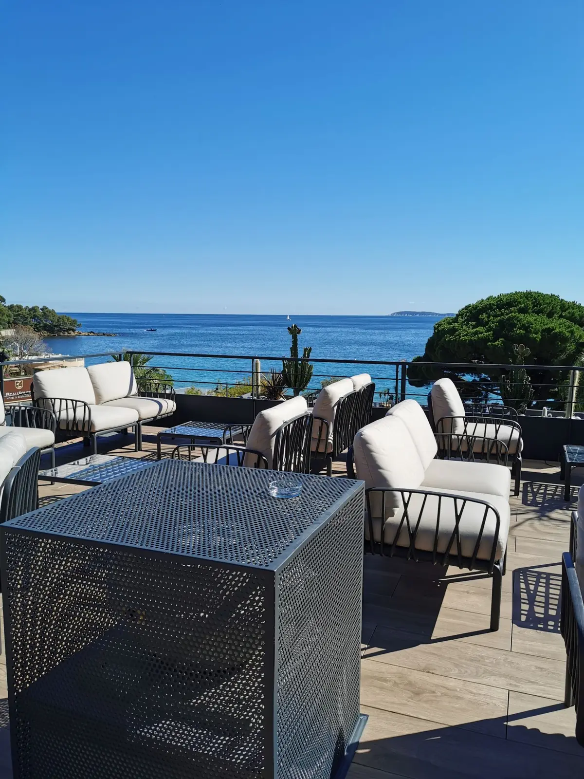 Salon extérieur du rooftop de l'hôtel Les Alcyons, garde-corps acier et vue sur la baie du Lavandou